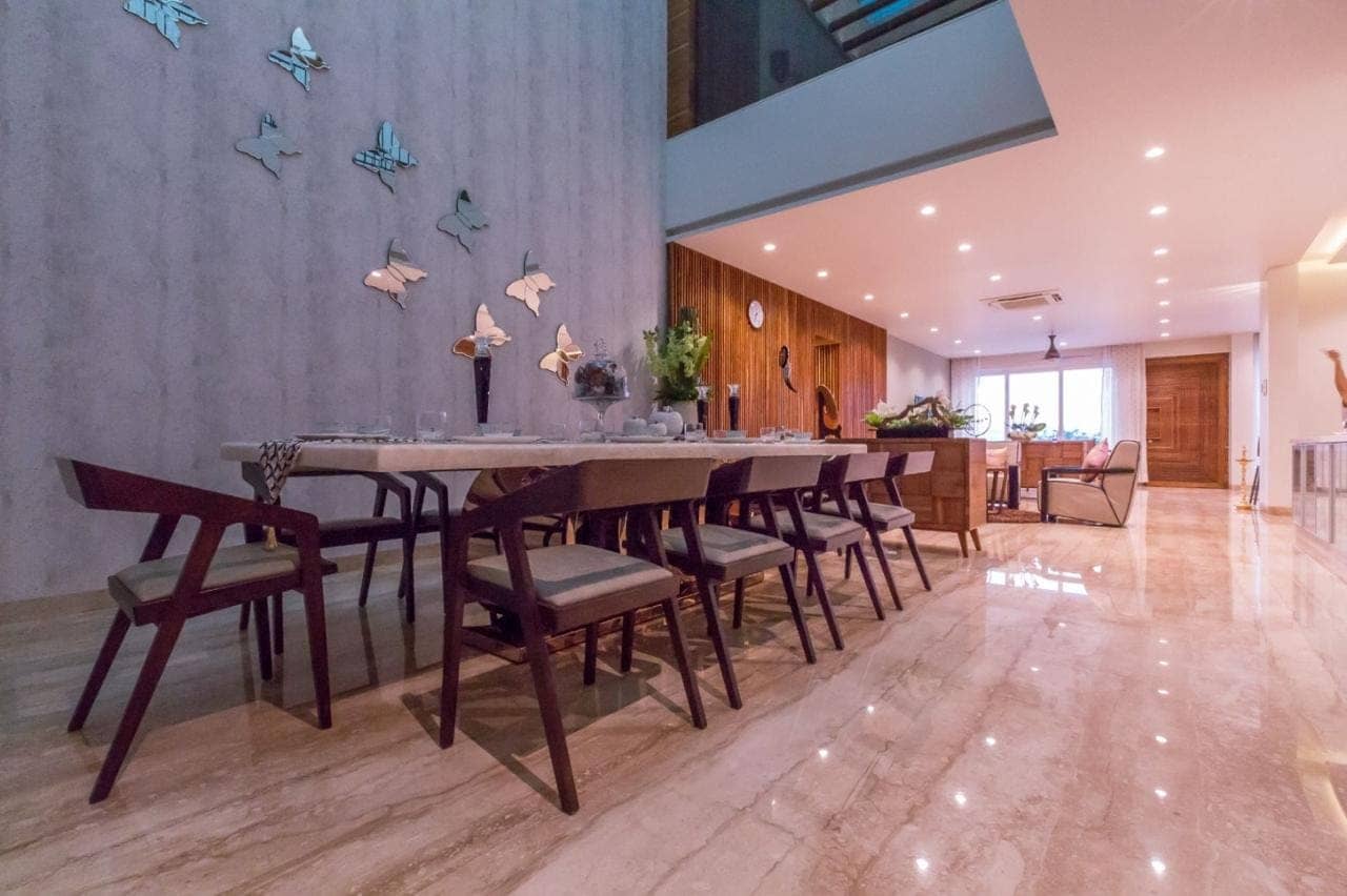 Double-height dining space with a custom table and decorative wall feature